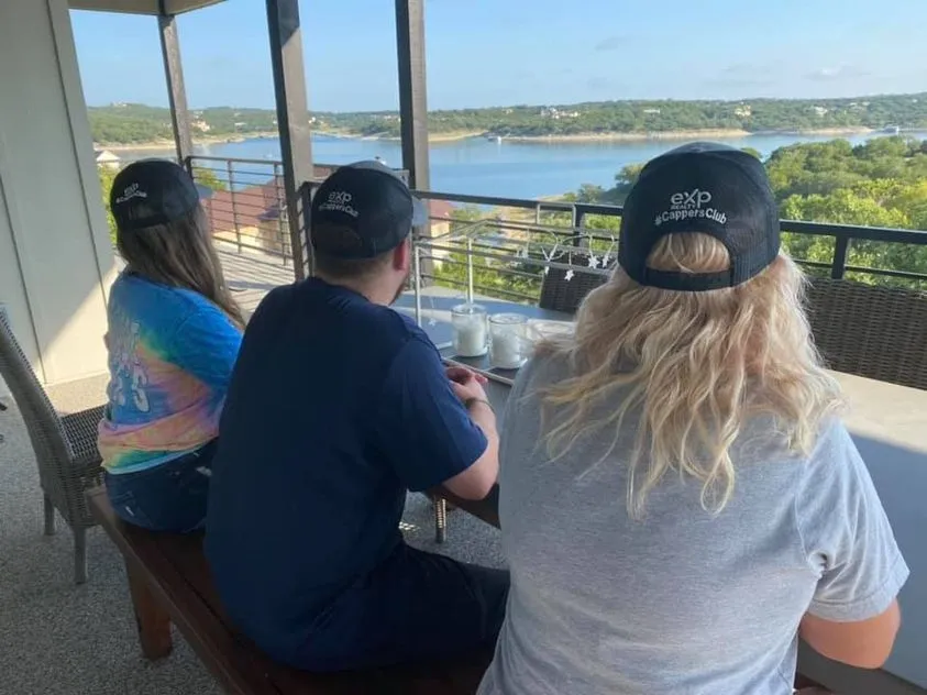 Agents in eXp Cappers Club hats overlooking a lake